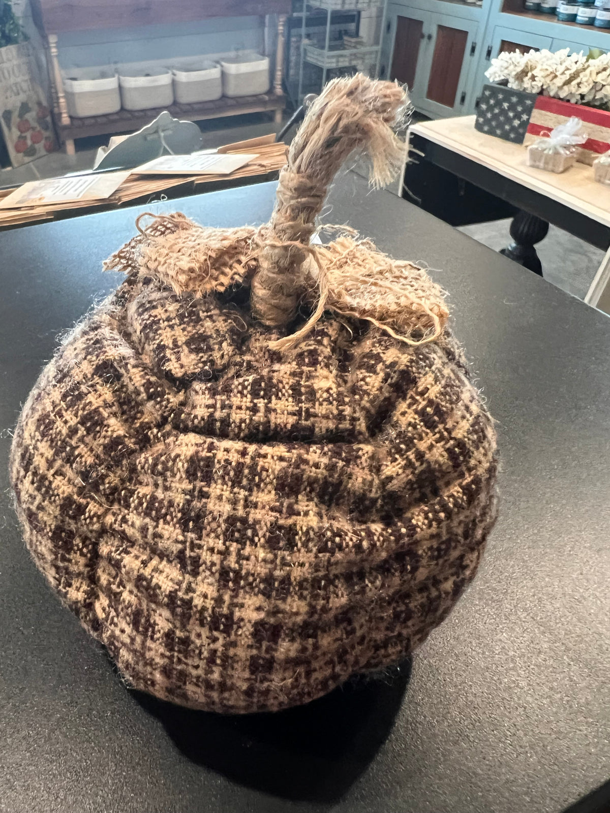 A decorative plush pumpkin in a country plaid. Black and beige with burlap bow and rope stem. 
