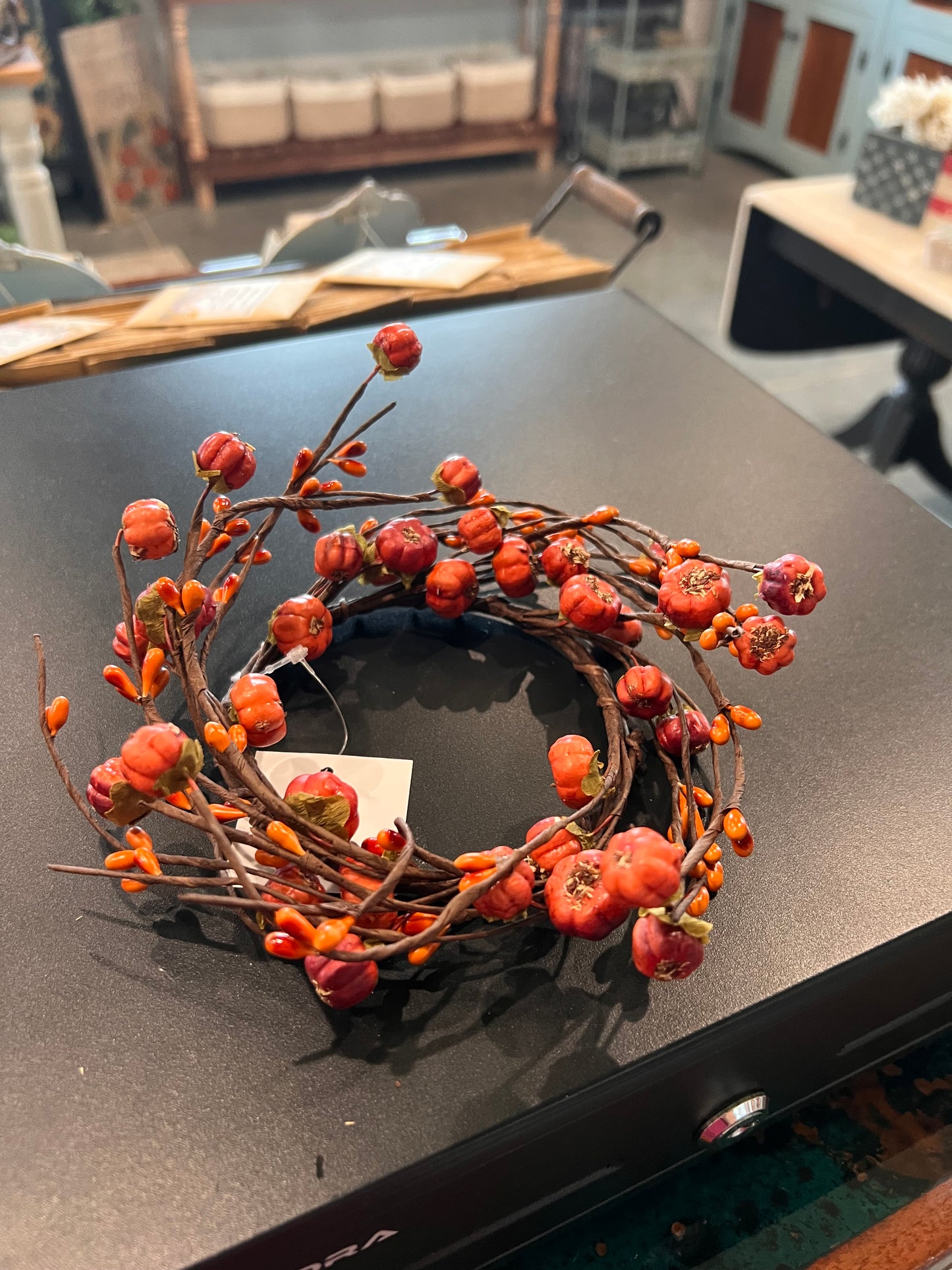 Twisting brown vines are filled with warm orange pip berries and petite pumpkin-like pods in shades of orange.