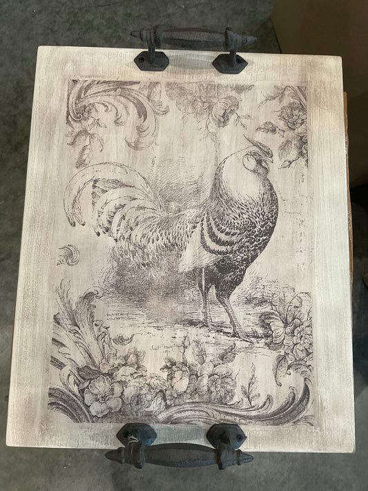 Rustic wooden tray is distressed white with a vintage look rooster and cast iron handles. Measures 15” x 19”