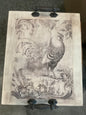 Rustic wooden tray is distressed white with a vintage look rooster and cast iron handles. Measures 15” x 19”